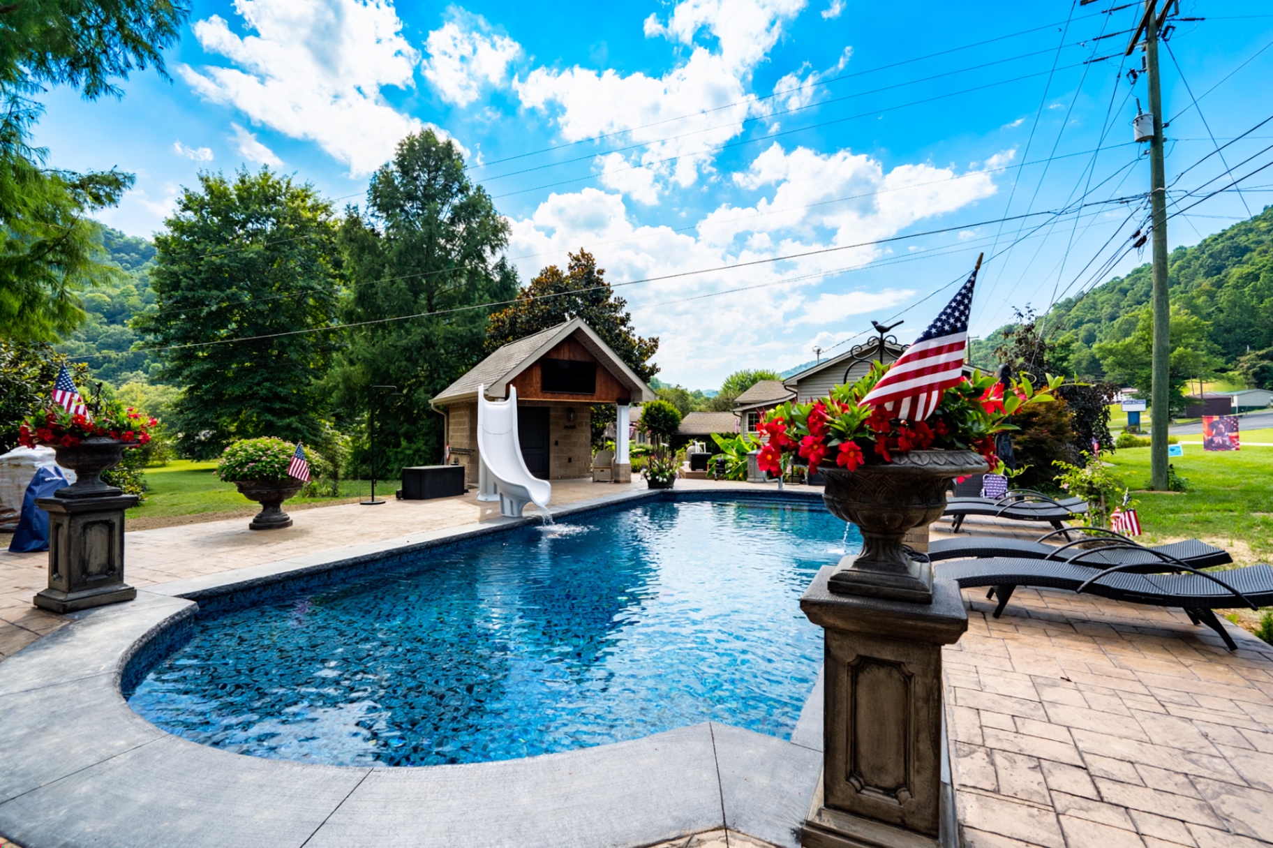 Custom in-ground swimming pool build by Blue Diamond in Pikeville, KY, with paver deck, slide, and mountain backdrop
